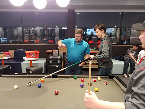 The team had fun playing with the pool table at the hotel. One of the parents is very good at pool and taught the students the how to play better.