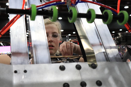 A student inspecting the robot between matches